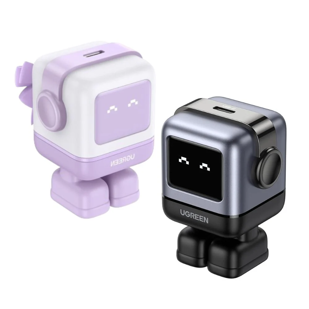 Two UGREEN Nexode RG GaN chargers shaped like small robots, one in white and purple and the other in metallic grey and black, featuring pixel-art smiling faces on their LED screens.